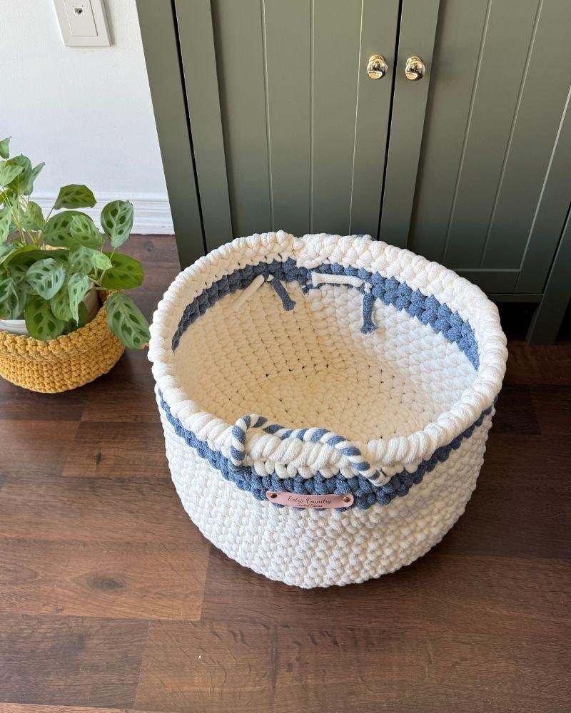 White woven basket on a wooden floor next to a green cabinet, Blue Off White