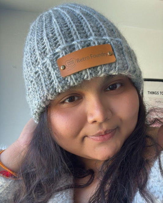 Person wearing a handmade beanie with a leather patch labeled 'Retro Foundry', Gray