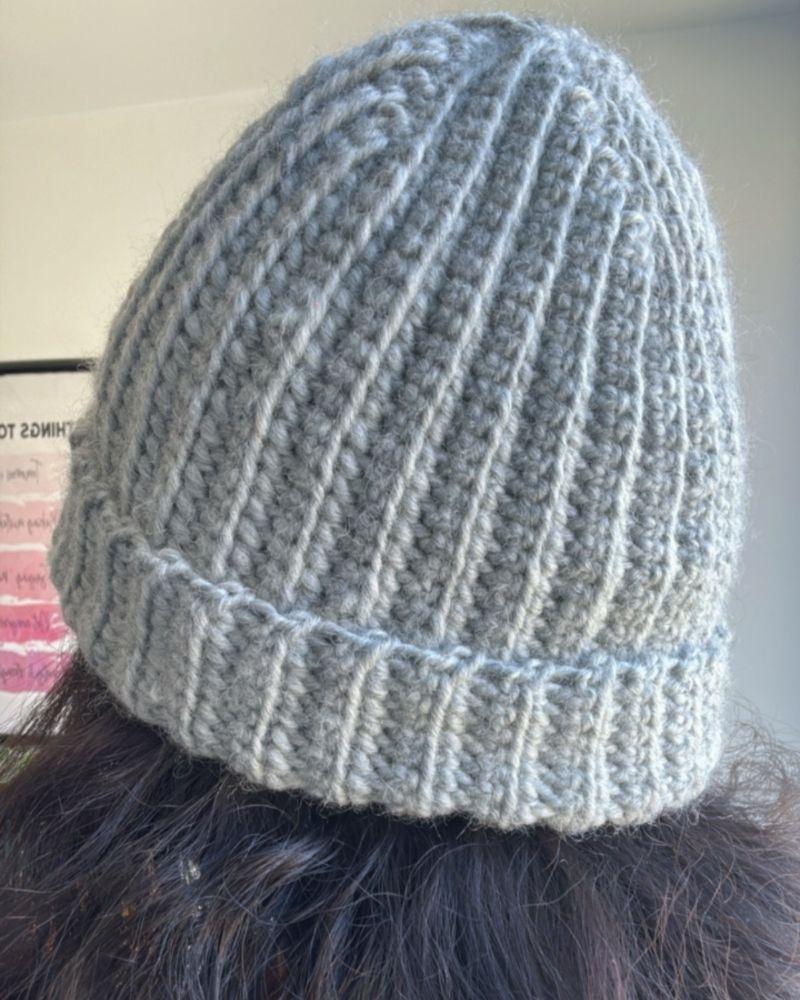Person wearing a handmade beanie with a leather patch labeled 'Retro Foundry', Gray